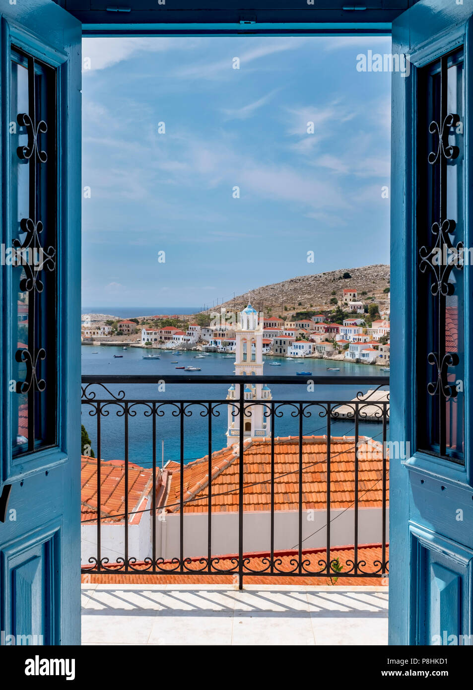 La vista migliore di Halki porto attraverso una in legno di colore blu del telaio della porta. Foto Stock