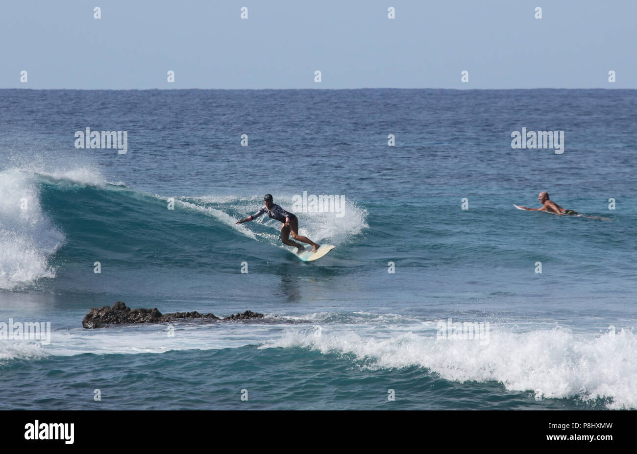 Navigare in sicurezza - evitare le rocce. Surfers cercando il loro sport sulle onde dell'oceano off Spiaggia sabbiosa a Halona Cove. Spiaggia di sabbia, Halona Cove, Oahu Island, ha Foto Stock