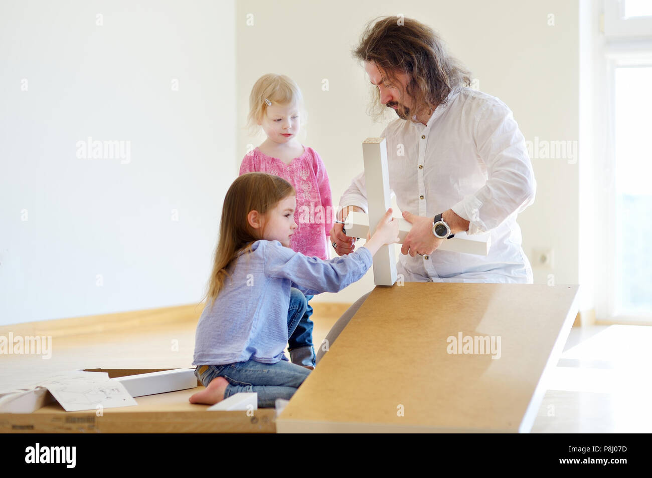 Padre Felice e le sue due figlie assemblando una tabella insieme Foto Stock