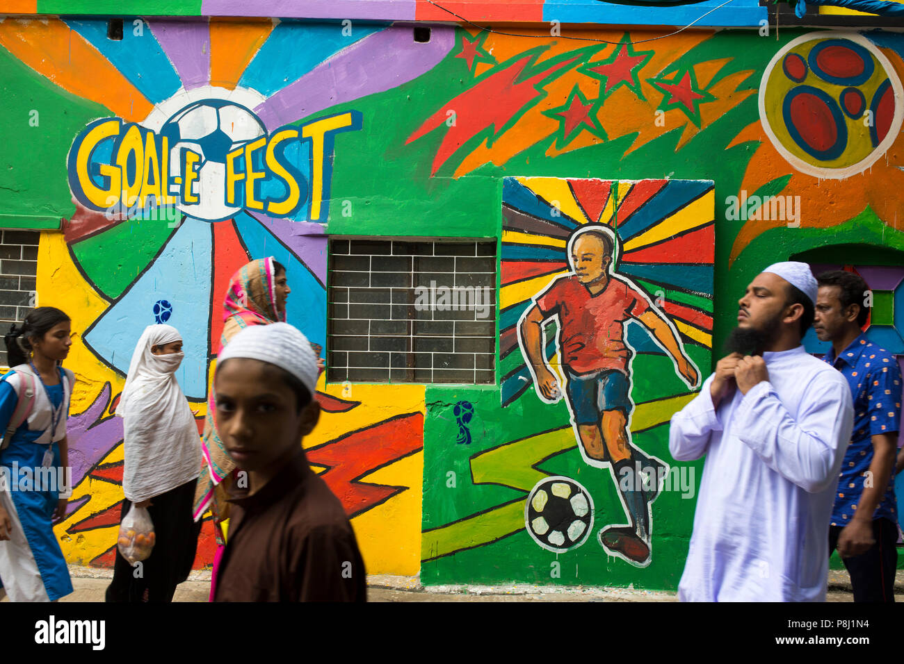 Dacca in Bangladesh - 10 Luglio : popolo del Bangladesh passeggiate attraverso accanto a una parete dipinta da appassionati di calcio durante il 2018 FIFA World Cup in Russia a Dhaka Foto Stock