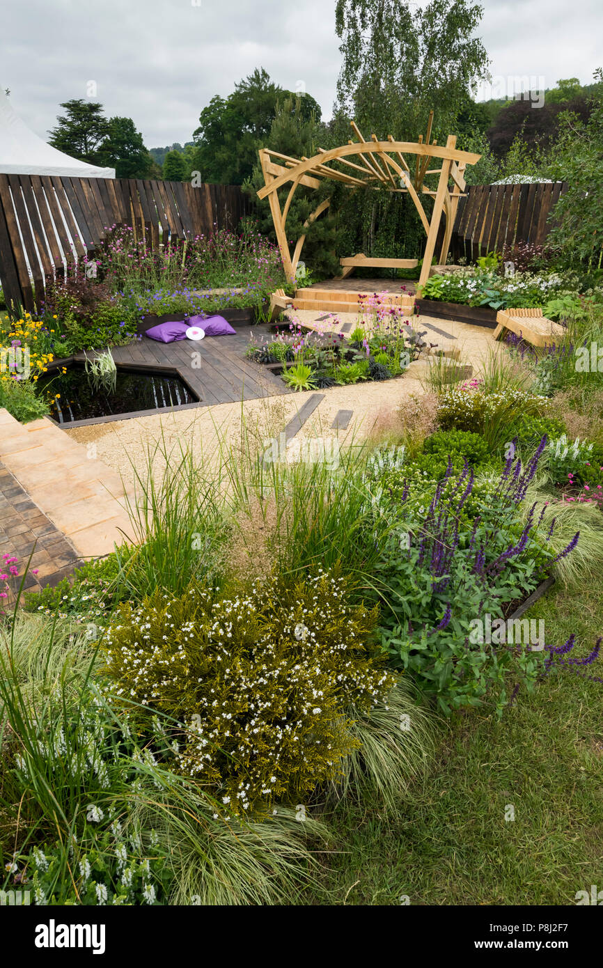 Fiori colorati, pergola in legno, da banco e da stagno in bella prize-winning giardino, i grandi spazi aperti - RHS Chatsworth Flower Show, Inghilterra, Regno Unito. Foto Stock