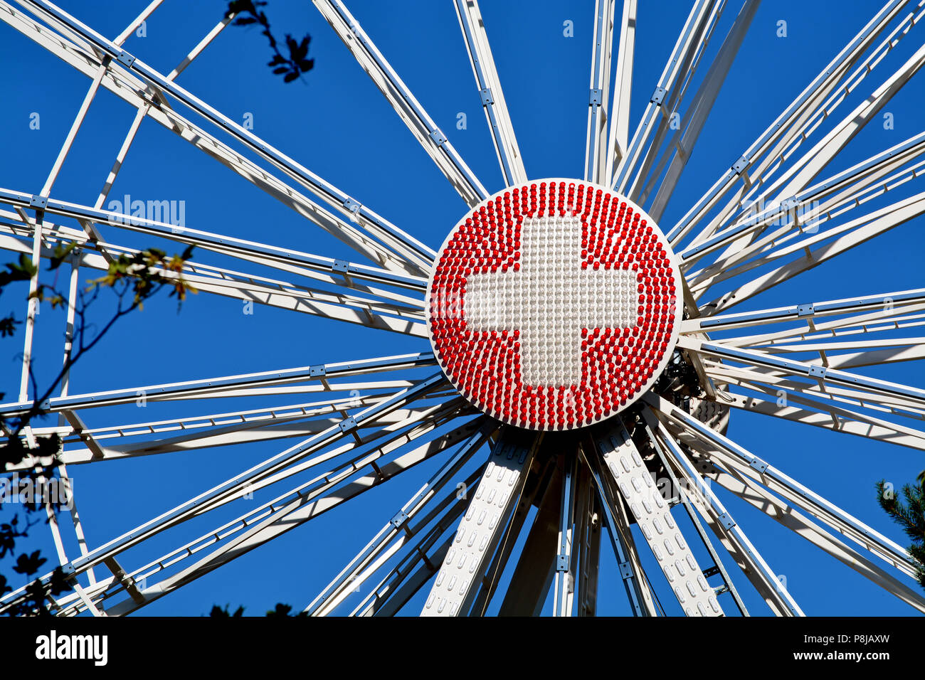 Primo piano di una ruota panoramica Ferris a Ginevra, in Svizzera, con il round pezzo centrale fatta di rosso e di luci bianche configurato in una bandiera svizzera. Foto Stock