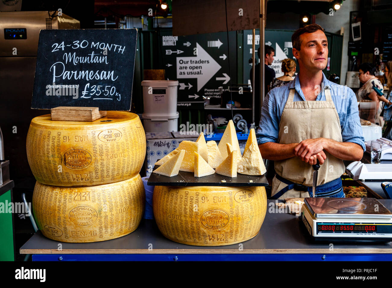 Un uomo la vendita di formaggio in un formaggio in stallo nel mercato di Borough, Londra, Inghilterra Foto Stock