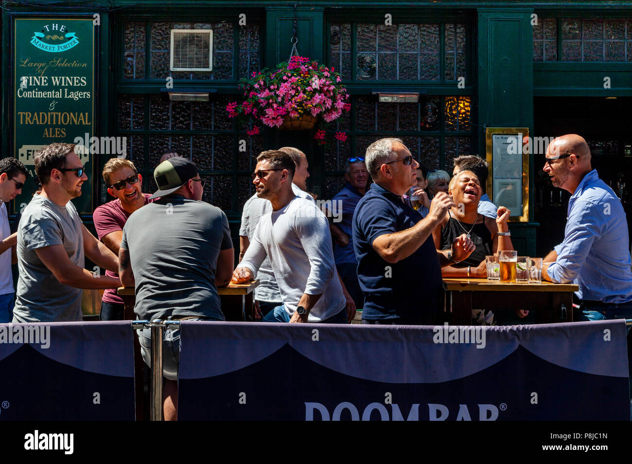 Felice, ridendo per coloro che godono di un ora di pranzo bere al di fuori del mercato Porter Pub nel mercato di Borough, Londra, Inghilterra Foto Stock
