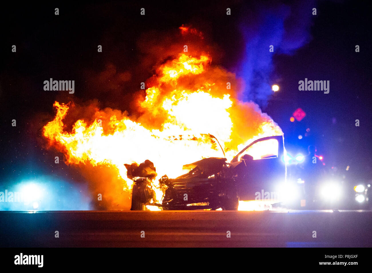 Incendio sulla vettura durante la notte con le luci della polizia in background noone Foto Stock