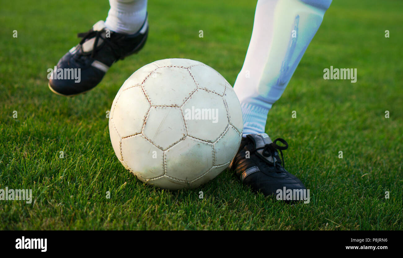 Close up foto delle gambe di un giocatore di calcio che è sparare la palla su erba verde Foto Stock