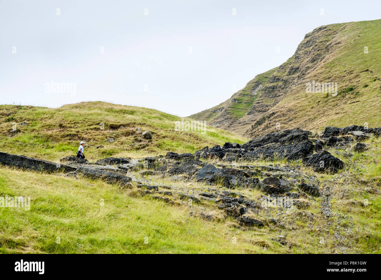 Cerca fino a una persona a piedi lungo parte della vecchia crollato road (A625) sotto Mam Tor danneggiato molte volte da frana, Derbyshire, England, Regno Unito Foto Stock