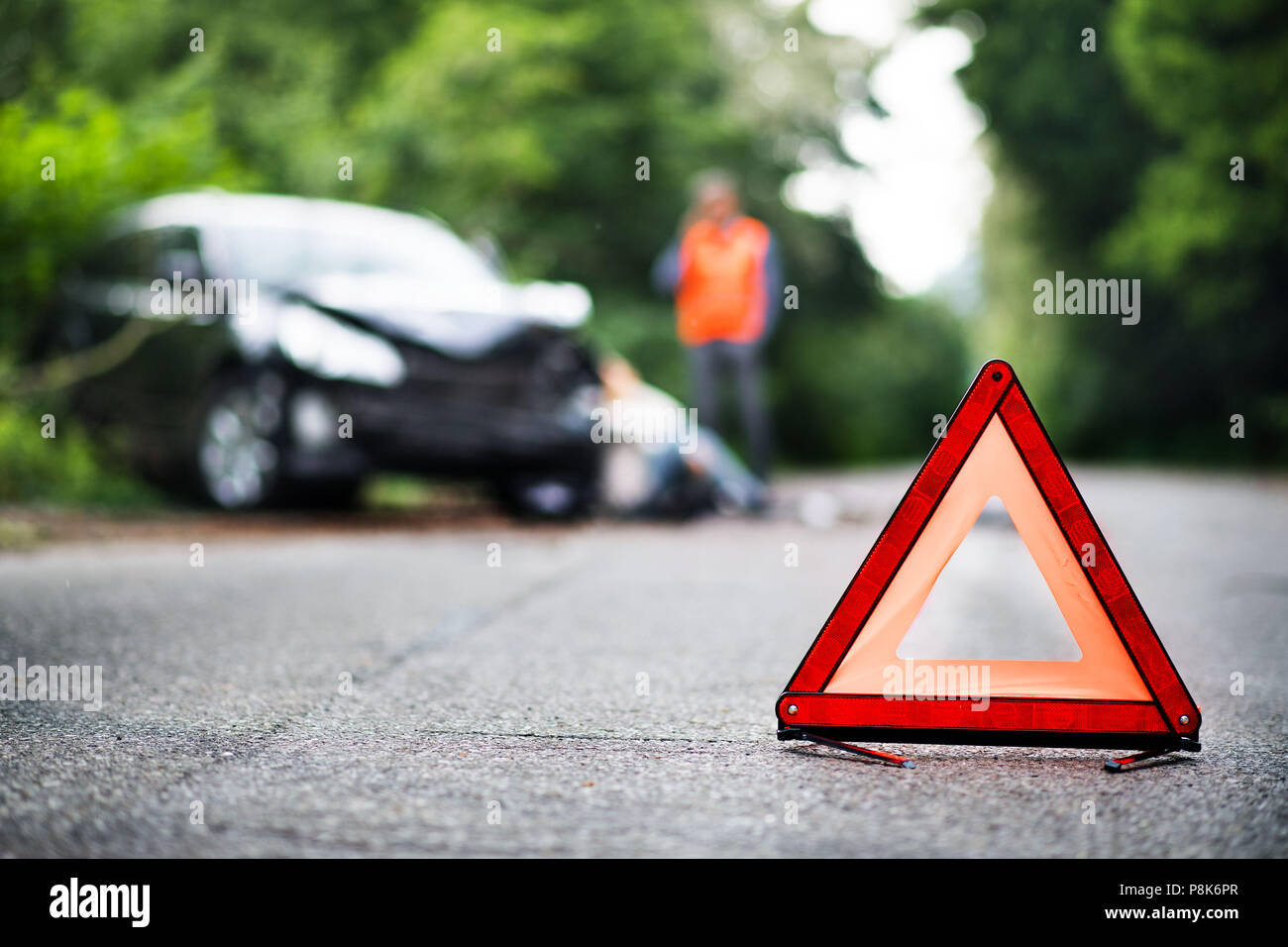 Una chiusura di un rosso triangolo di emergenza sulla strada di fronte ad una vettura dopo un incidente. Foto Stock