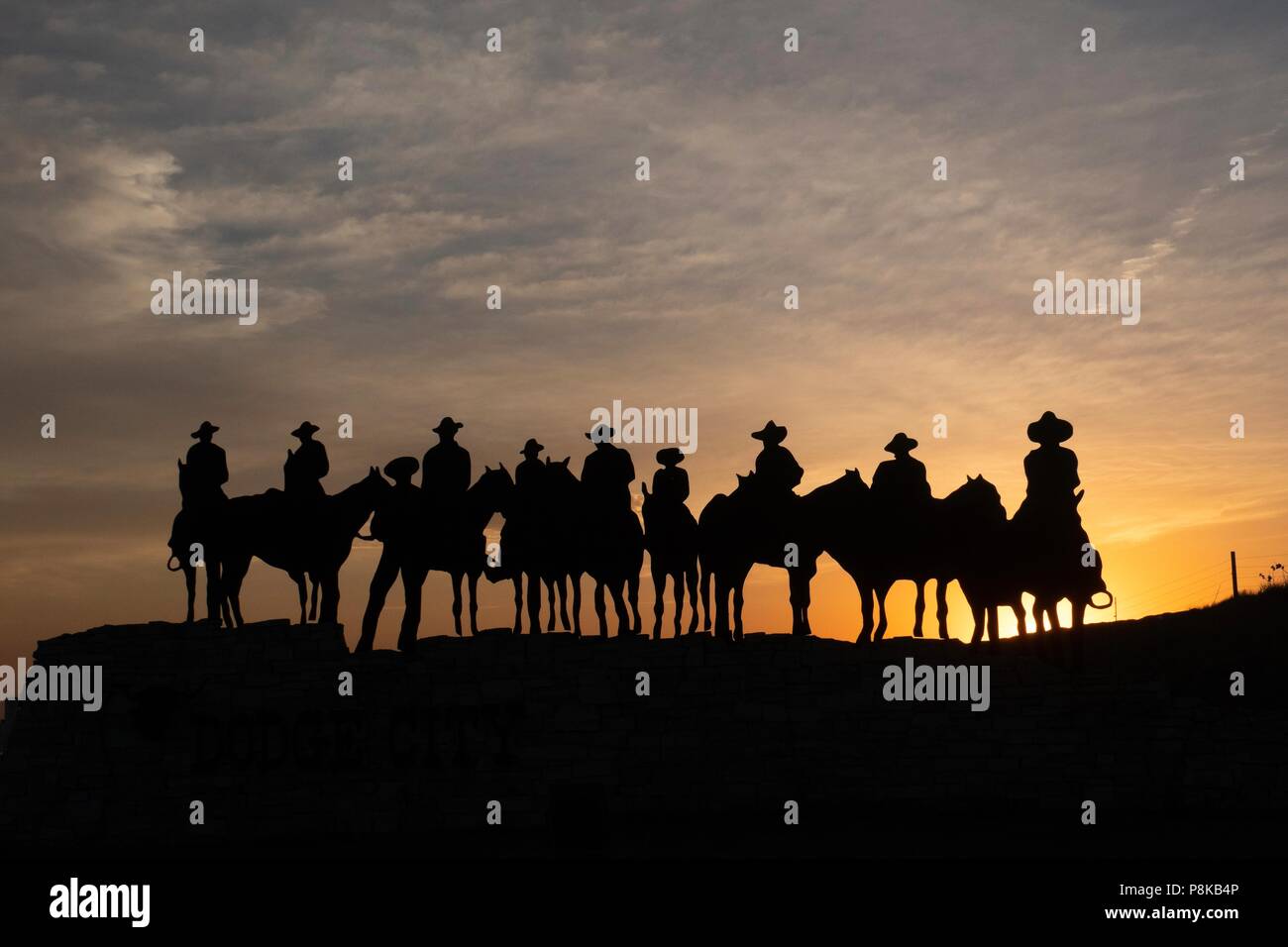 Silhouette di scultura del cowboy a cavallo al tramonto in Dodge City, Kansas Foto Stock