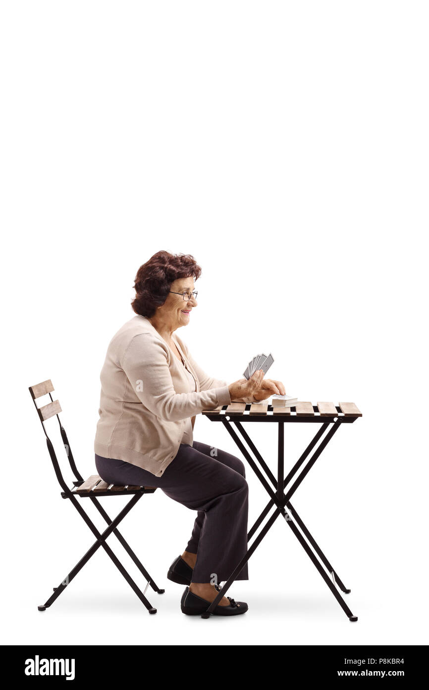 Senior signora seduta su un tavolo e giocare a carte isolati su sfondo bianco Foto Stock
