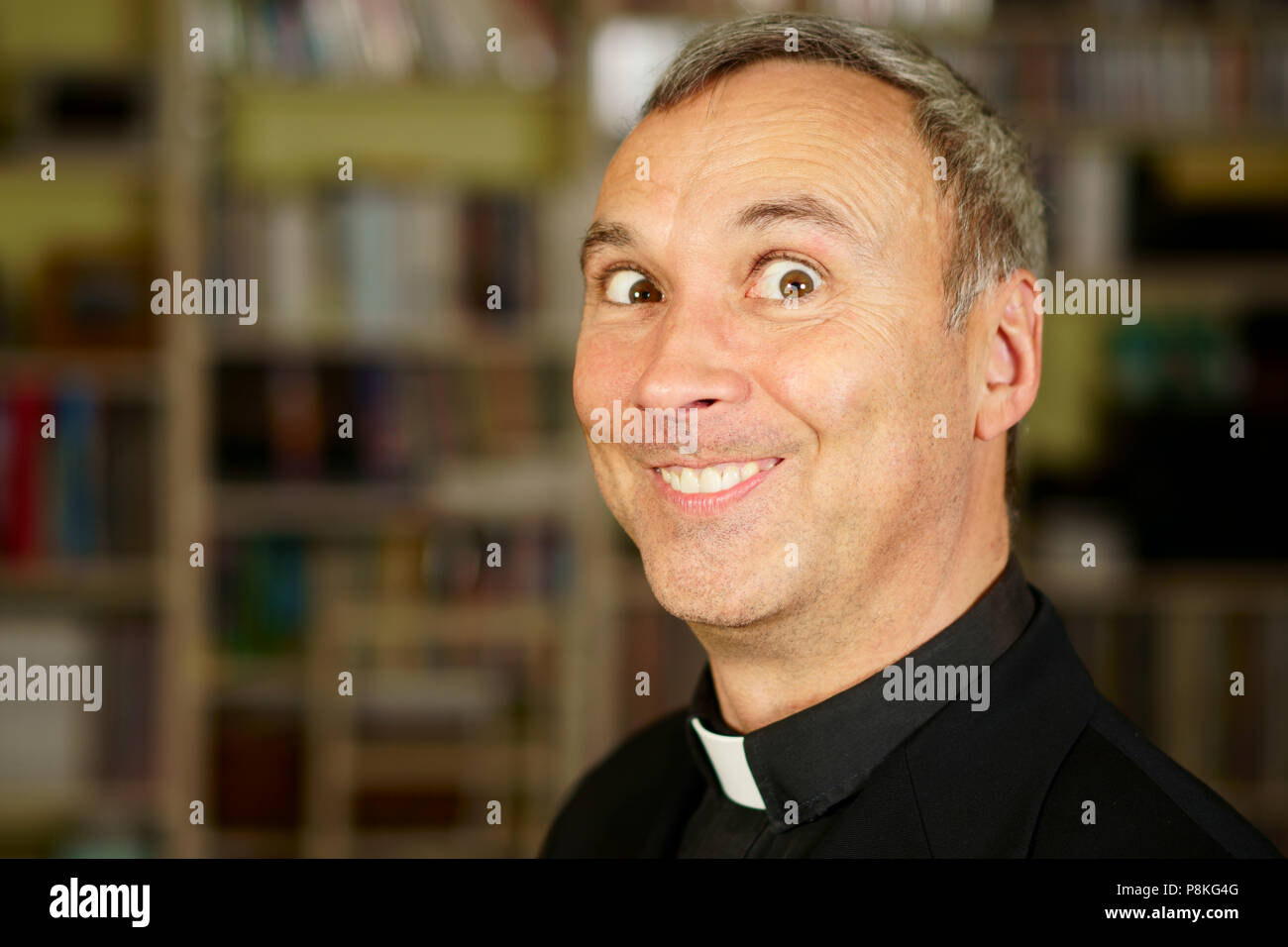 Una buona ricerca crazy sacerdote cattolico è nella sua libreria. Ha un look stolto. Foto Stock