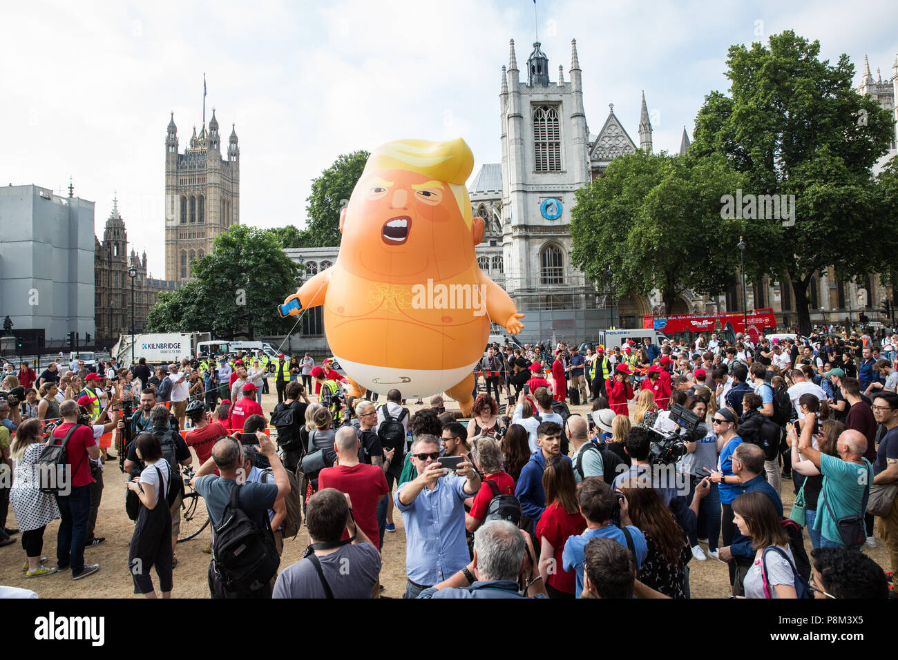 Londra, Regno Unito. 13 Luglio, 2018. Gli attivisti Anti-Trump sollevare Trump Baby, a 6 metro di altezza di elio-gonfiabile riempito raffiguranti Donald Trump come un arancio con capelli baby in pannolini, sopra Piazza del parlamento in segno di protesta contro la visita nel Regno Unito del Presidente Trump. È stato concesso il permesso per la protesta gonfiabile per il sindaco di Londra Sadiq Khan. Credito: Mark Kerrison/Alamy Live News Foto Stock