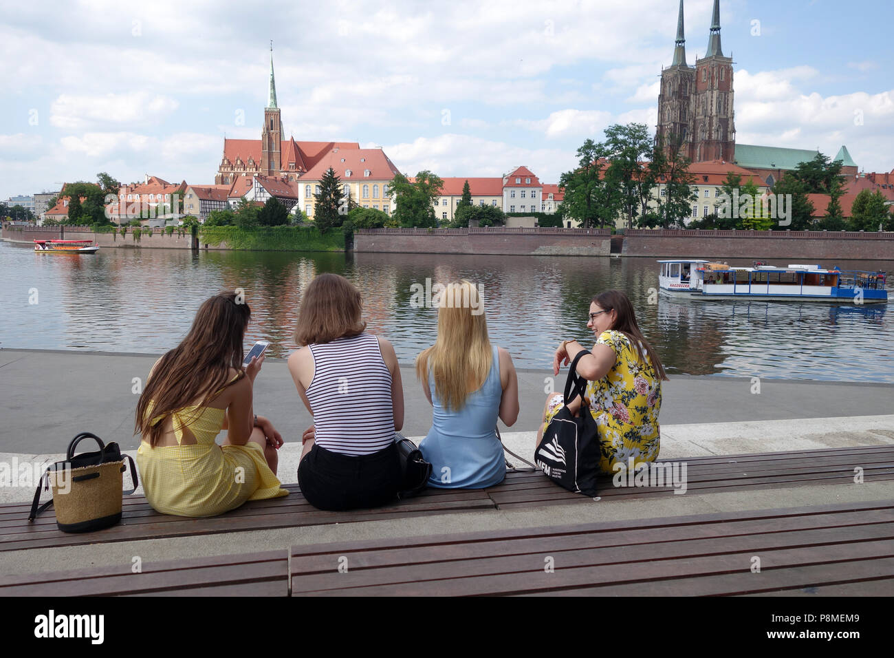 Giovani donne ragazze gente seduta dal fiume Oder e Isola della cattedrale di Wroclaw Polonia Foto Stock
