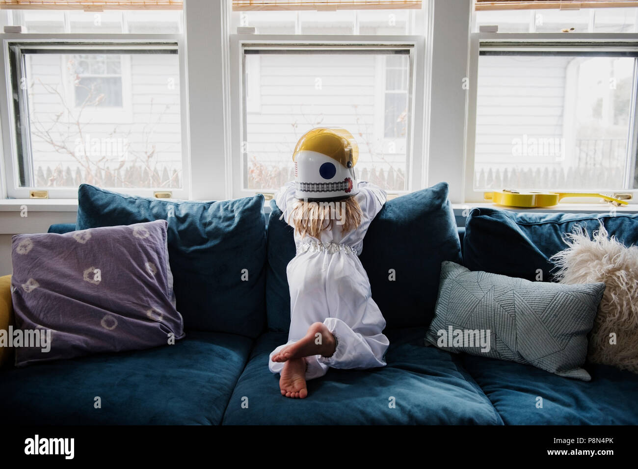 Ragazza che indossa il casco sul divano vicino alla finestra Foto Stock