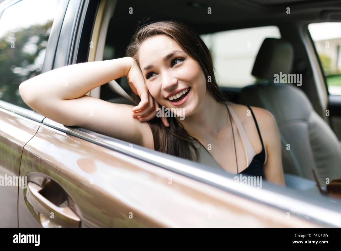 Sorridente giovane donna seduta in auto Foto Stock