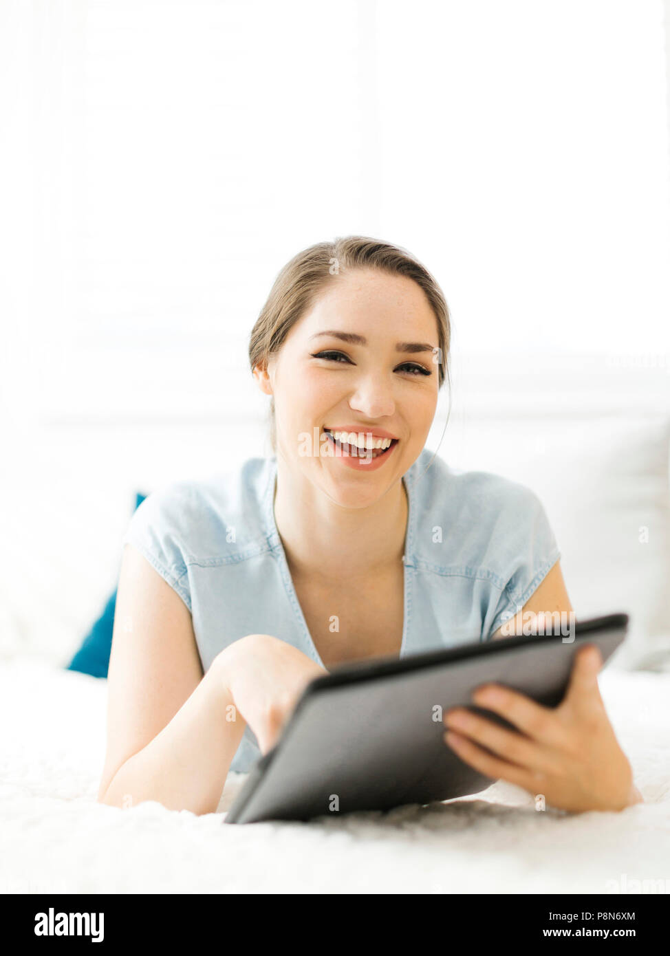 Donna sorridente che tiene la cartella sul letto Foto Stock