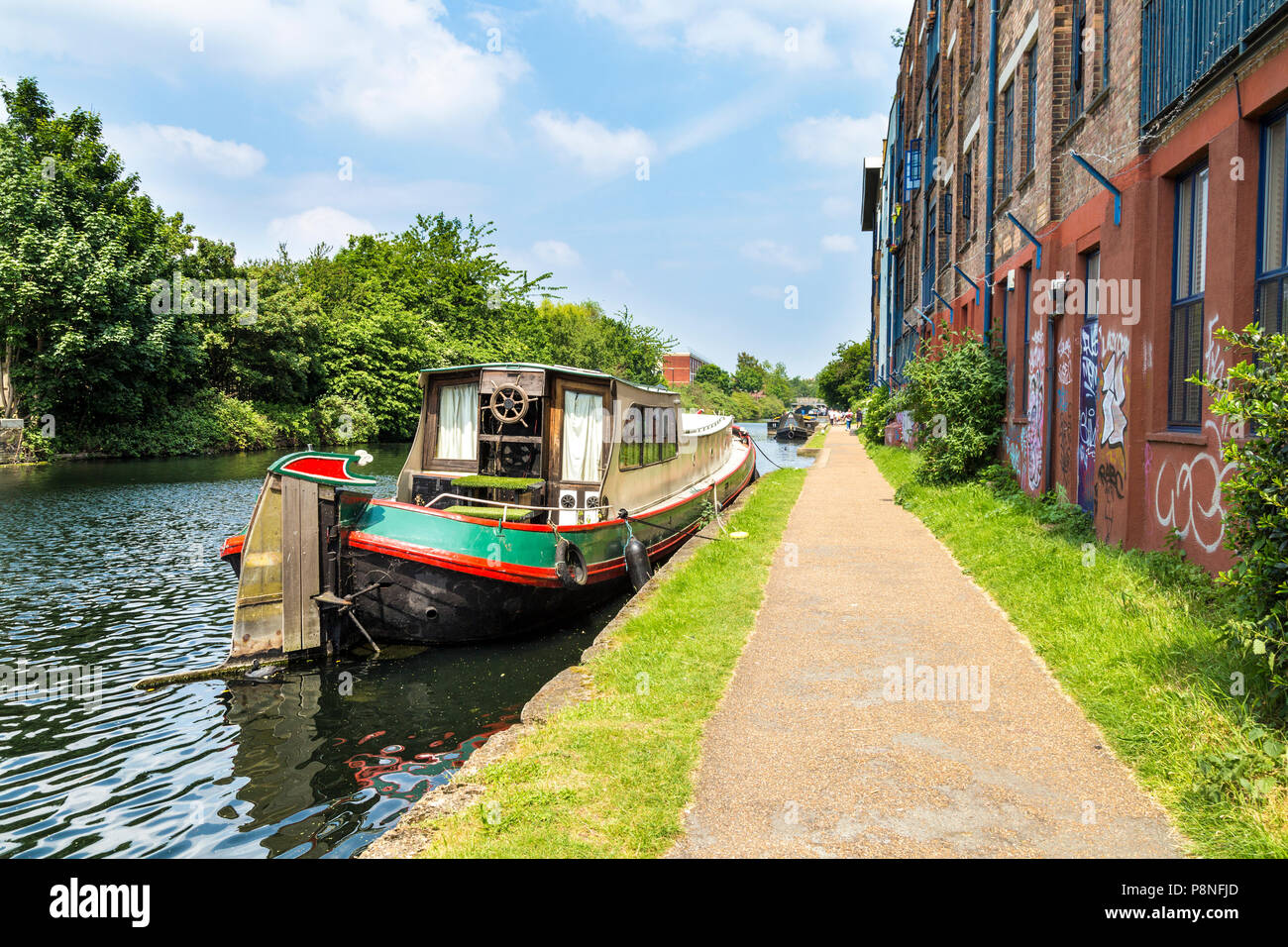 Un ormeggio narrowboat sul Regents Canal accanto ad edifici di magazzino, London, Regno Unito Foto Stock