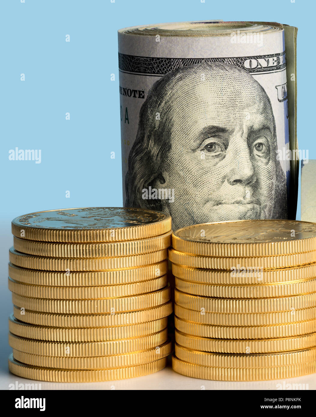 Monete d'oro puro davanti a banca di rotoli di valuta statunitense Foto Stock