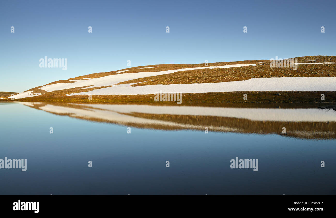 Colline si riflettono in un lago a un'altitudine elevata altopiano nel nord della Norvegia Foto Stock
