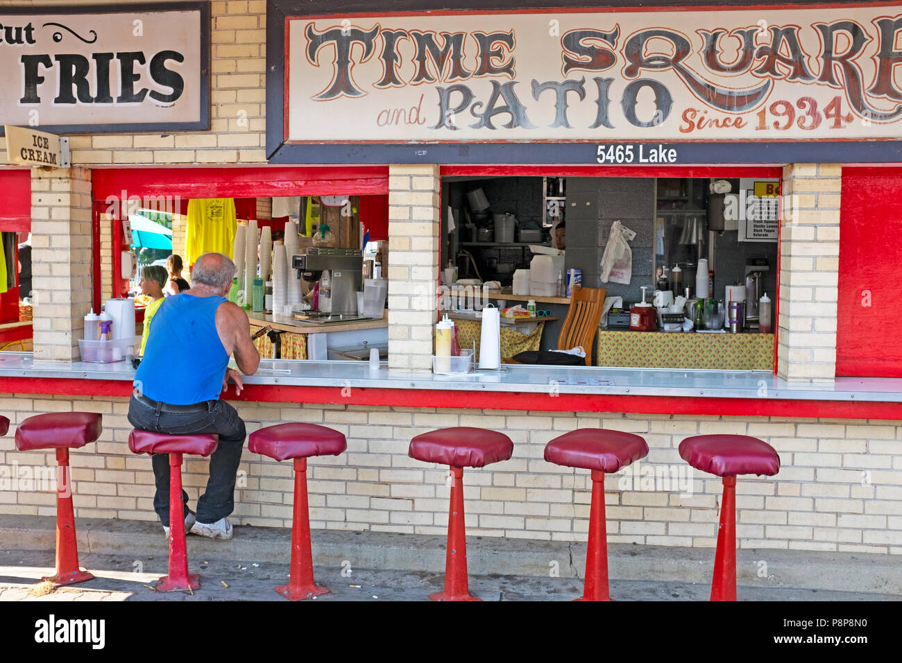Un singolo uomo si siede in una vecchia scuola di marciapiede esterno diner con sgabelli in Ginevra-su-il-Lago boardwalk durante l'estate in Ginevra-su-il-Lago,Ohio Foto Stock