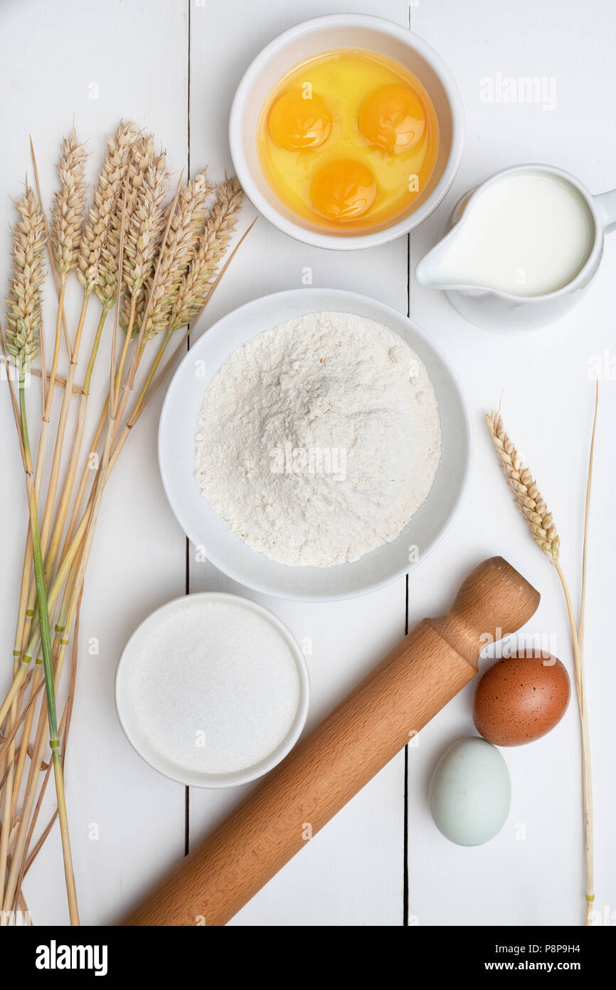 Il frumento e la cottura Ingredienti su un bianco sullo sfondo di legno Foto Stock