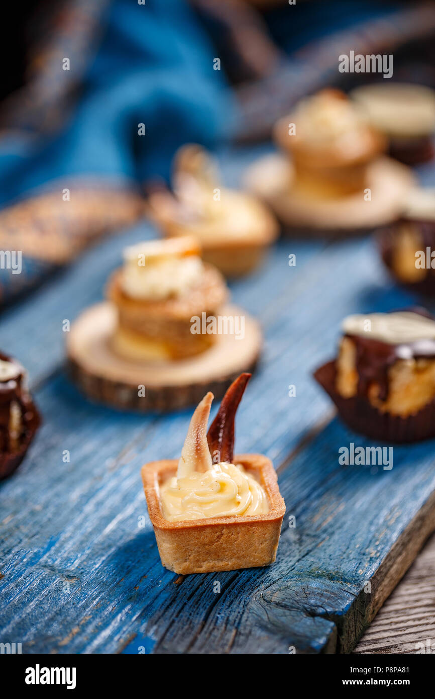 Crostata al limone blu sulla tavola di legno, altro piccolo dessert sullo sfondo Foto Stock