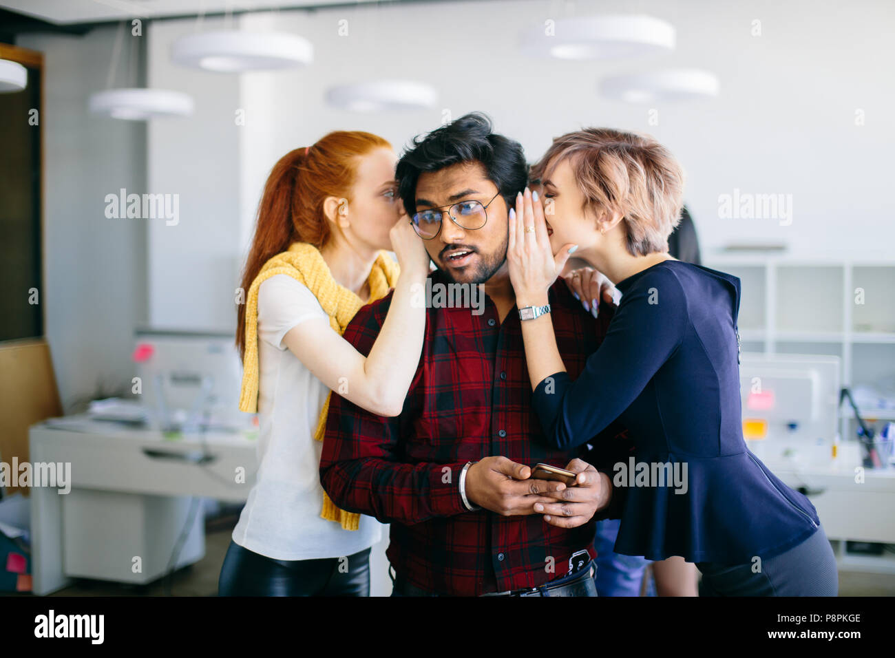 Closeup ritratto di zenzero e biondo donne raccontando i segreti per il loro collega indù. backstage collusione. intrighi al lavoro Foto Stock