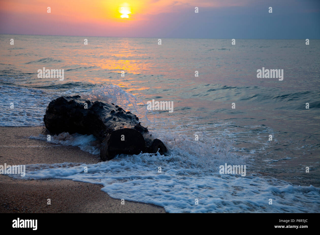 Bel mare al tramonto. Spray e log sullo sfondo del sole giallo. Seascape. Foto Stock