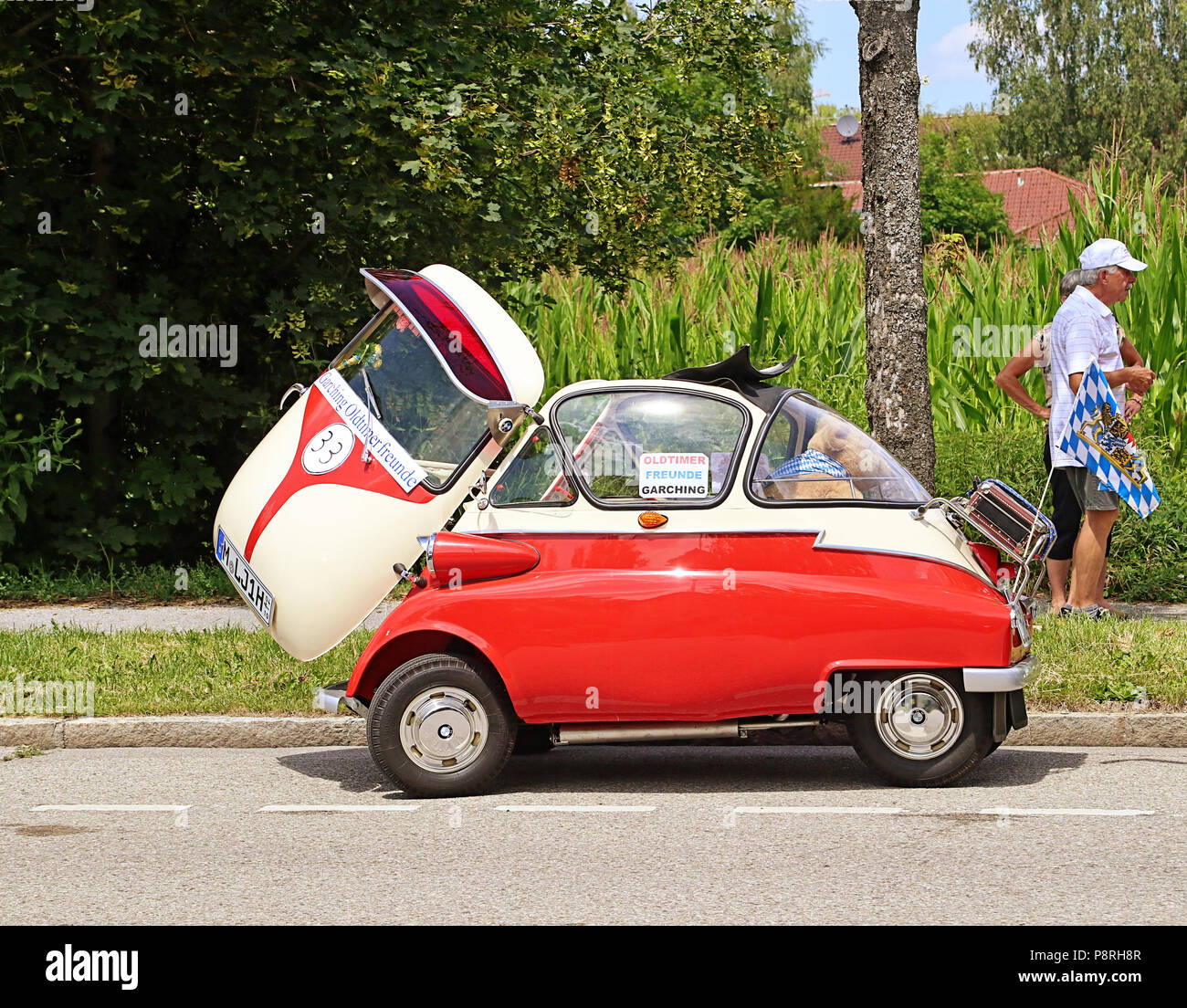 A Garching, Germania-luglio 8, 2018. Auto d'epoca BMW Isetta 300 bicolore rosso e bianco crema con porta aperta e aprire il tetto del sole presso la tradizionale sfilata f Foto Stock