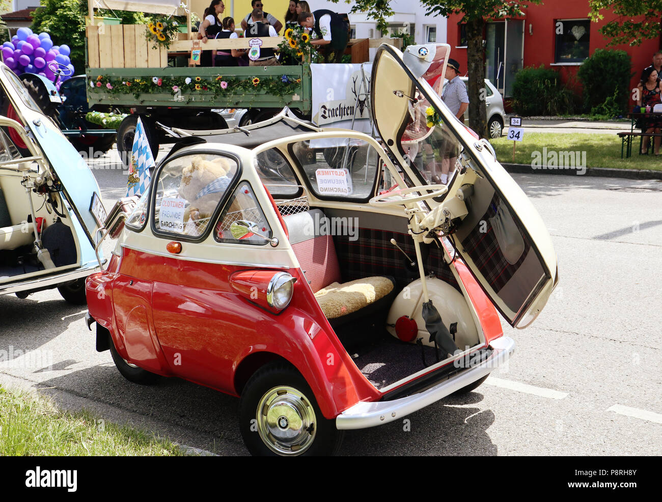 A Garching, Germania-luglio 8, 2018. Auto d'epoca BMW Isetta 300 bicolore rosso e bianco crema e con lo sportello aperto e aprire il tetto del sole al Parad tradizionali Foto Stock