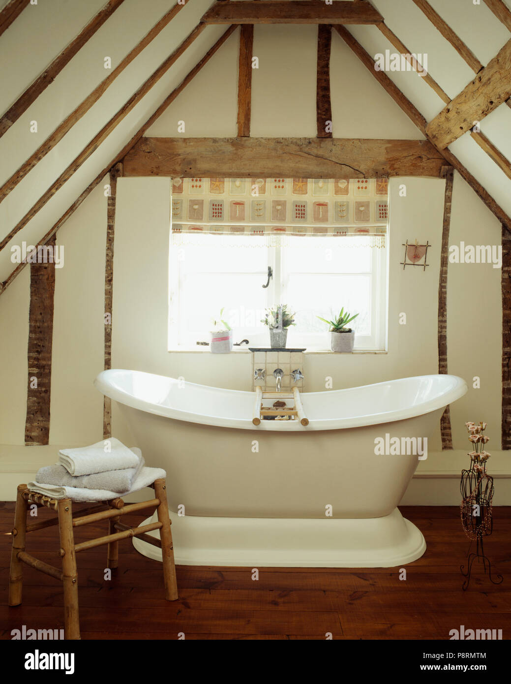 Cilindro tradizionale-top bagno in un bianco bagno travi sotto il cornicione di una soffitta di conversione in un periodo house Foto Stock