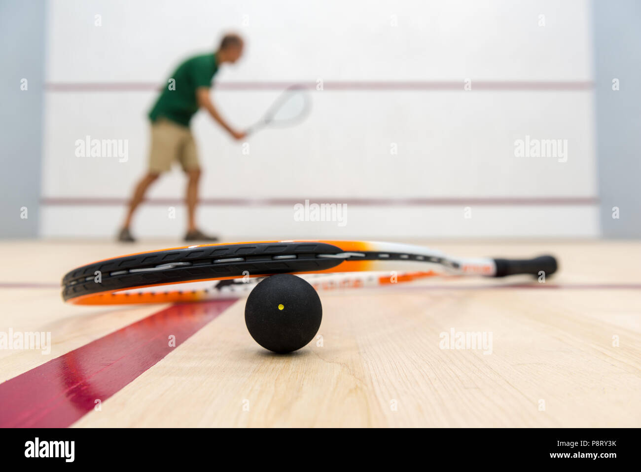 Racchette da squash giacente sulla sfera con il giocatore in background Foto Stock