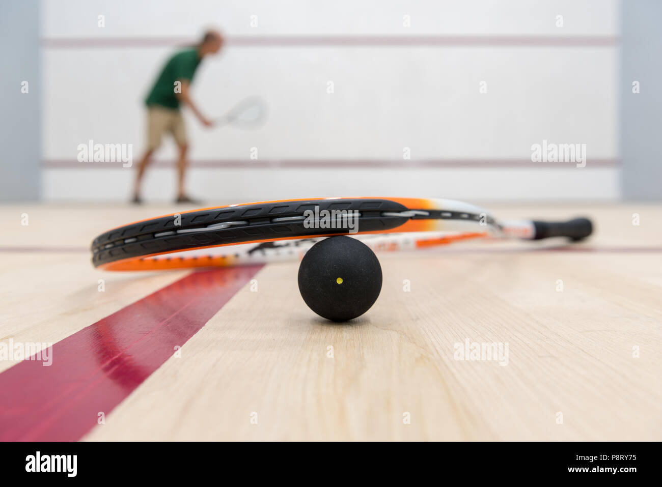 Racchette da squash giacente sulla sfera con il giocatore in background Foto Stock