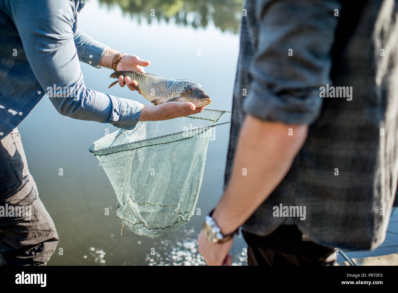 Fisherman ottenere catturati pesci provenienti dalla rete da pesca vicino al lago al mattino Foto Stock