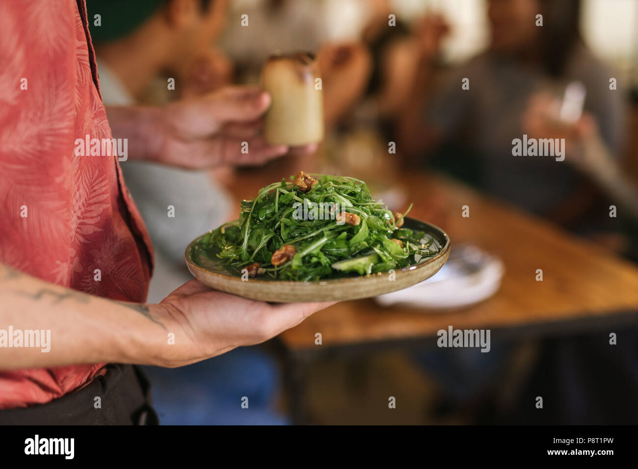 Cameriere che serve una sana insalata per i clienti del ristorante Foto Stock