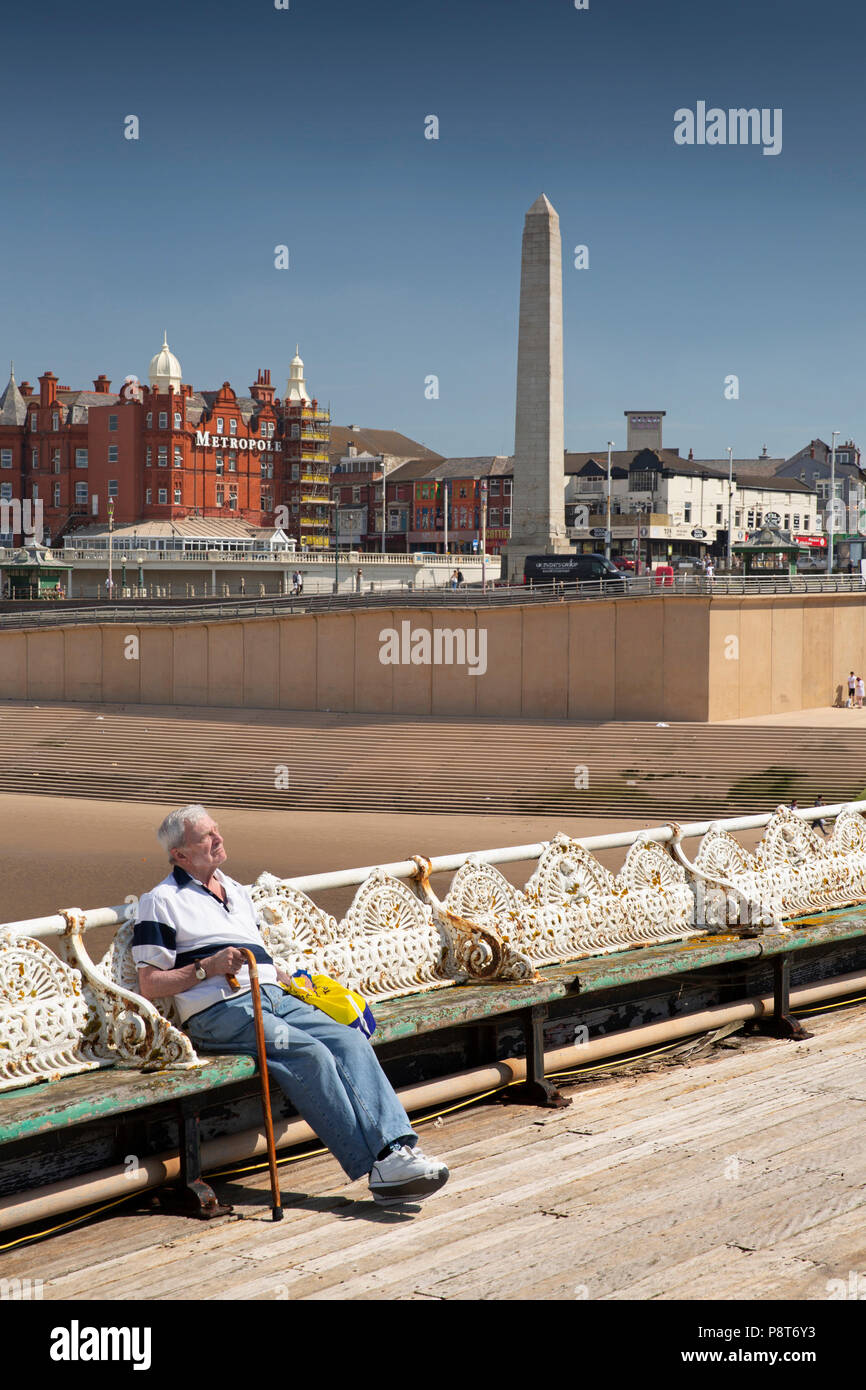 Regno Unito, Inghilterra, Lancashire, Blackpool, North Pier visitatore sat sul banco di lavoro godendo del sole Foto Stock