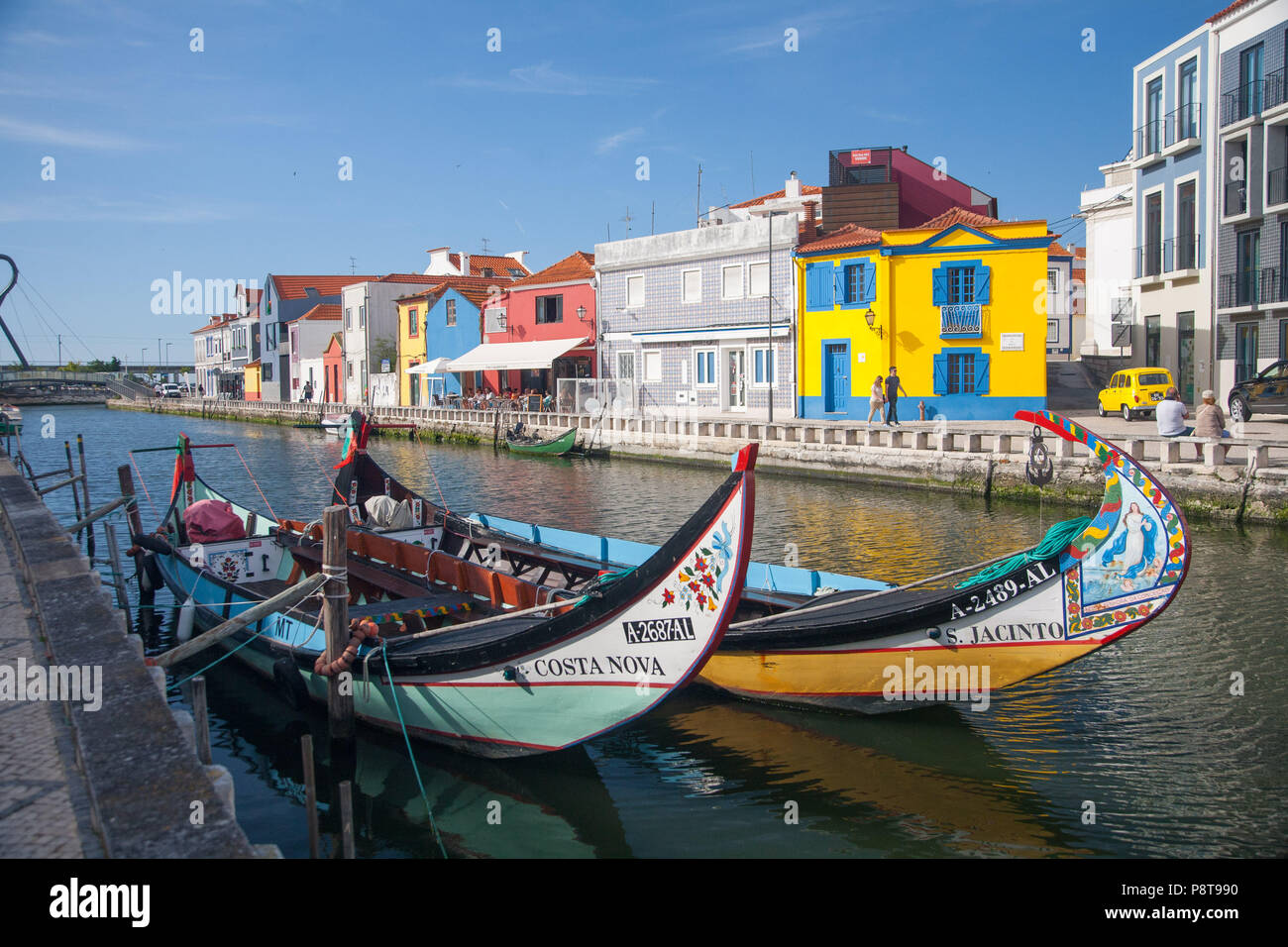 Due Moilceiros colorati (barche originariamente utilizzato per raccogliere le alghe) ormeggiate vicino tradizionali case di pescatori su un canale in Aveiro, Portogallo Foto Stock