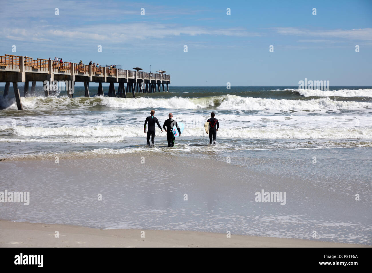 Tre surfers di uscire in acqua a Jacksonville Beach, Florida Foto Stock