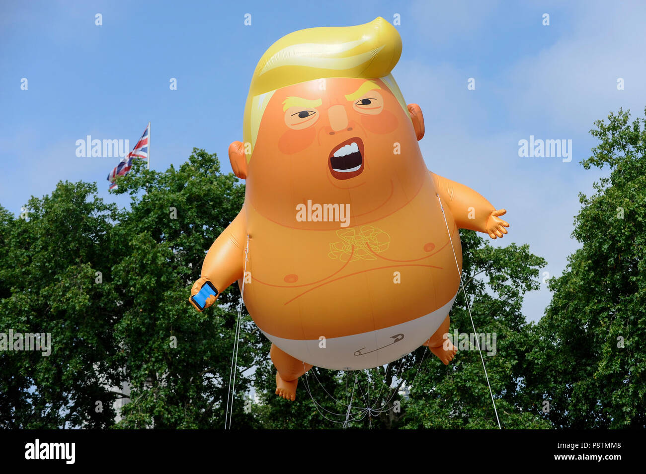 Londra, Regno Unito. Il 13 luglio 2018. Un gigante 'Trump Baby' palloncino vola sopra la piazza del parlamento di Westminster come parte di una protesta al presidente Donald Trump's visita al Regno Unito. Gli organizzatori hanno progettato il 6m di altezza blimp, volare ad una altezza di 30m, raffiguranti Donald Trump come un bambino con mani piccole, tenendo in mano un telefono cellulare e che indossa un pannolino. Proteste di massa sono anche tenuti a prendere posto nel centro di Londra in risposta alla visita del Presidente. Credito: Stephen Chung / Alamy Live News Foto Stock