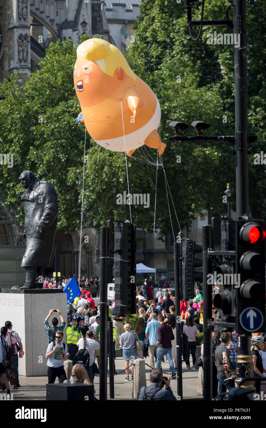 Londra, Regno Unito. 13 Luglio, 2018. Il palloncino gonfiabile chiamato Baby Trump vola al di sopra della statua del tempo di guerra Brish Primo Ministro Winston Churchill in piazza del Parlamento, Westminster, la sede del parlamento britannico, durante il Presidente degli Stati Uniti in visita al Regno Unito. Baby Trump è un 20ft alto arancio blimp raffigurante il presidente usa come un furioso, smartphone-frizione - infantile e dato il permesso speciale per appaiono sopra la capitale dal sindaco di Londra Sadiq Khan a causa della sua protesta piuttosto che di natura artistica. Essa è il frutto di graphic designer Matt Bonner. Foto di credito: RichardBaker/Alamy Live News Foto Stock