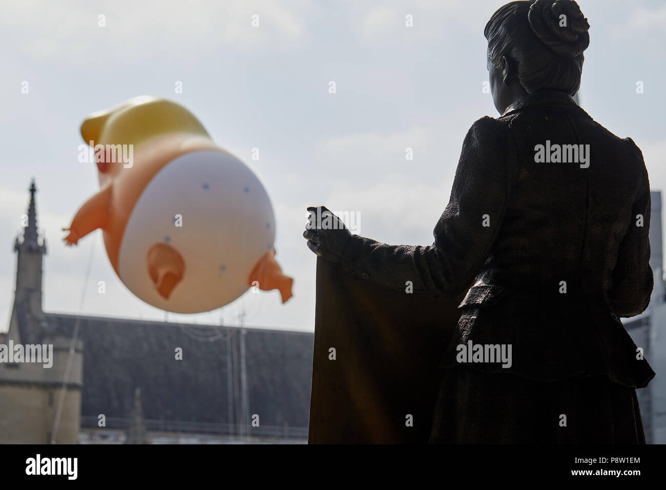 London, Regno Unito - 13 Luglio 2018: la statua di suffragist Millicent Fawcett guarda un palloncino beffardo Donald Trump in piazza del Parlamento, Londra. Foto Stock