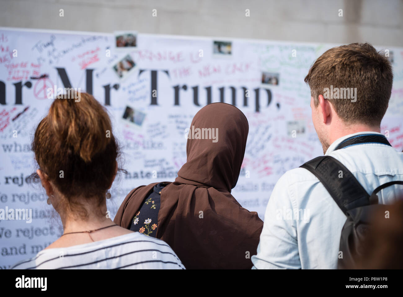 Persone che scrivono sulla parete Awaaz con commenti per Donald Trump. Decine di migliaia di persone hanno marciato e protestato contro la Trump visita al Regno Unito. Il mese di marzo è iniziato in Regent Street e si è conclusa a Trafalgar Square. Foto Stock