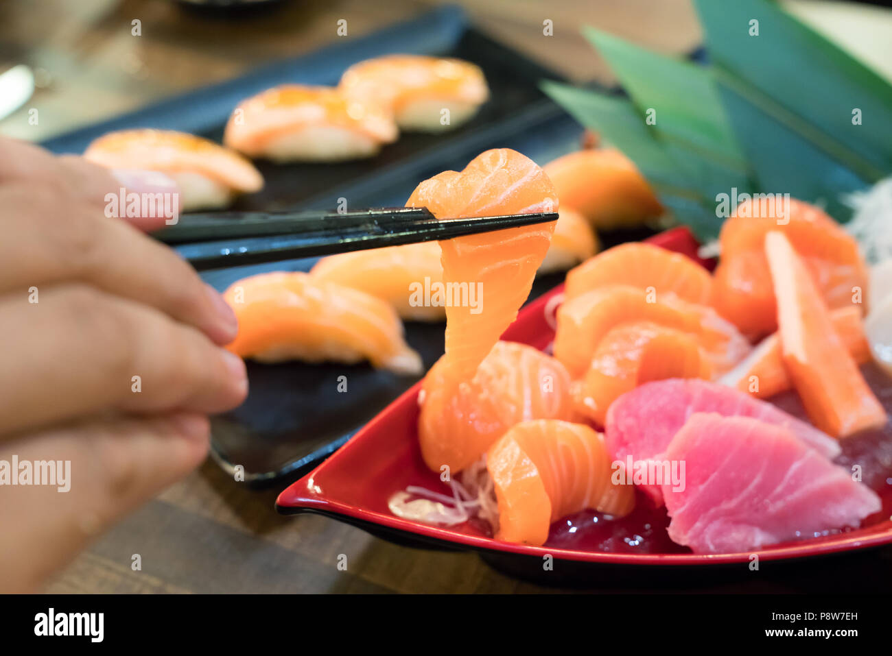 Bacchette con Sashimi con salmone e affettato misto sashimi di pesce su ghiaccio in nero ciotola. Il cibo giapponese in ristorante asiatico. Foto Stock