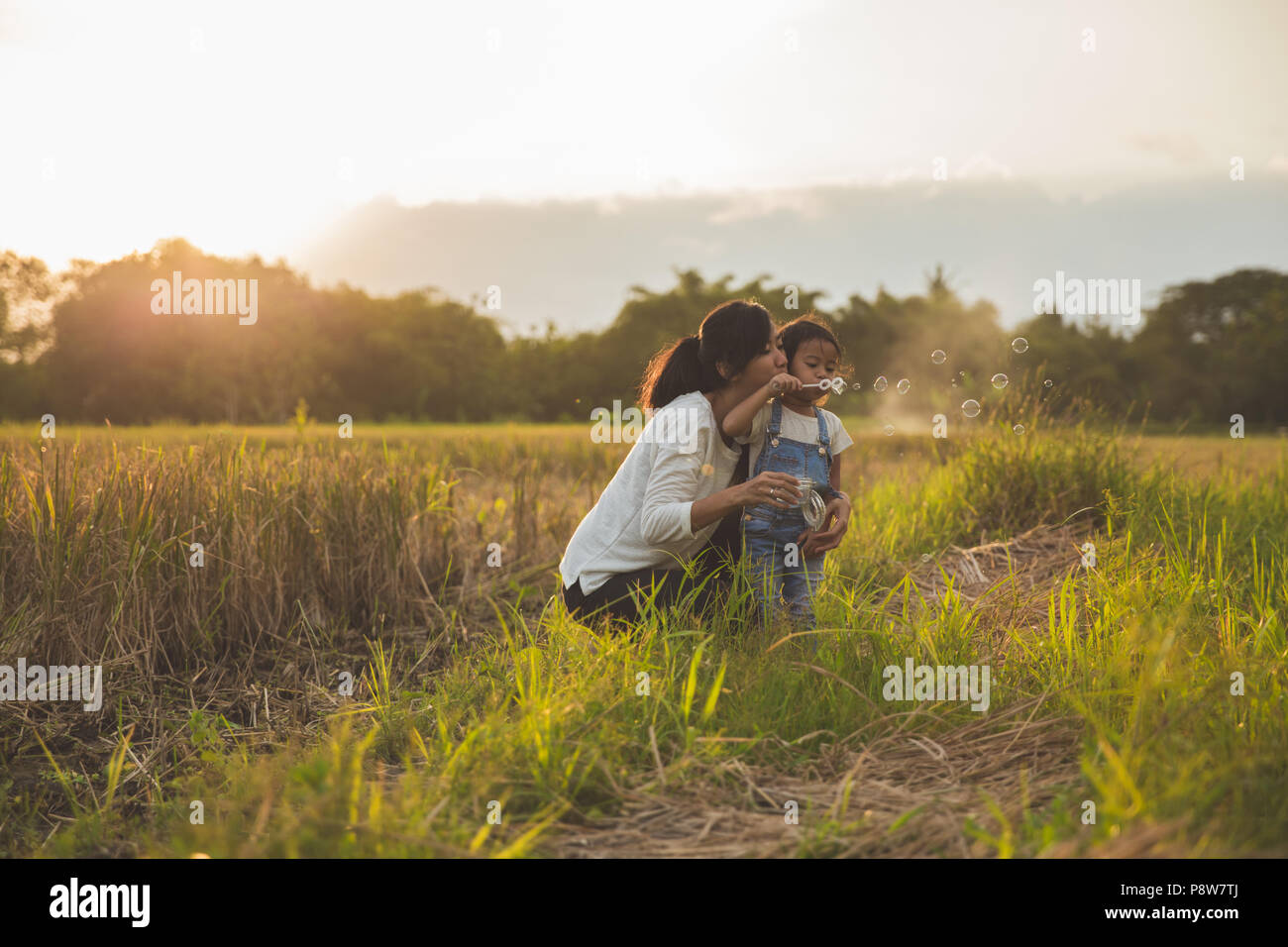 Mamma e Bambino gioca con bolla di risone di campo durante l'estate tramonto Foto Stock