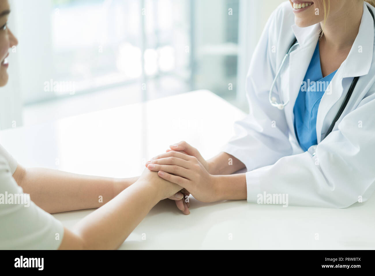 Donna Gentile Dottore mani tenendo la mano del paziente seduto alla scrivania di incoraggiamento, empatia, tifo e supporto durante la visita medica. Bad n Foto Stock