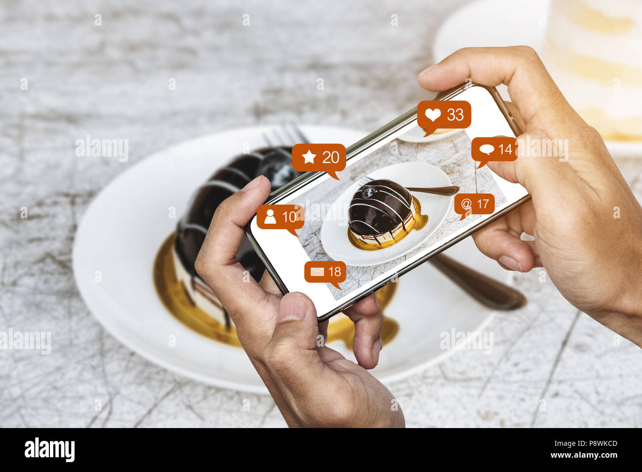 Tenendo il dessert fotografia di mobile smart phone e la condivisione sui social media, rete sociale con le icone di notifica Foto Stock