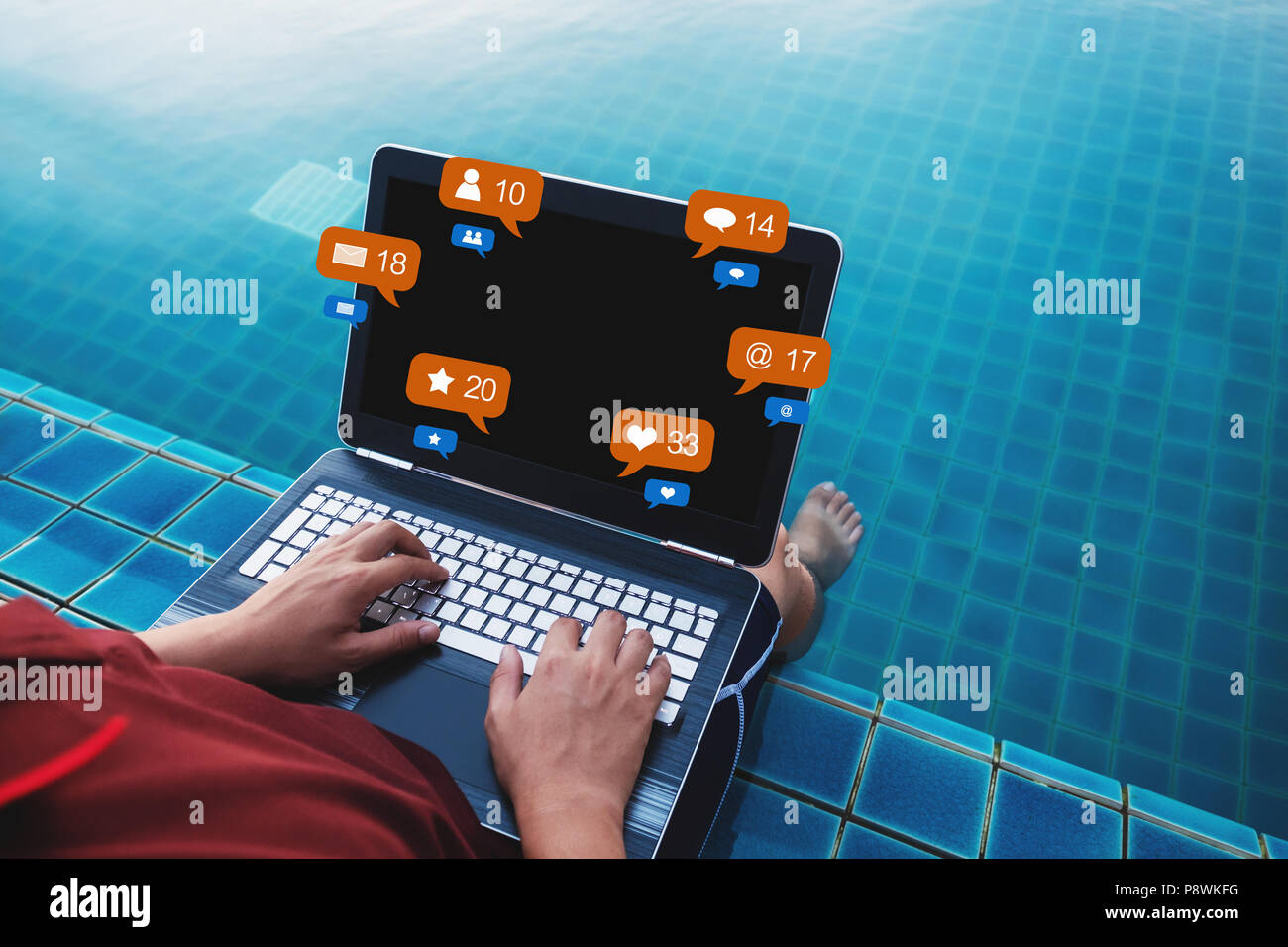 Un uomo che utilizza computer laptop a bordo piscina in estate vacanze, con i social media e social network le icone di notifica Foto Stock