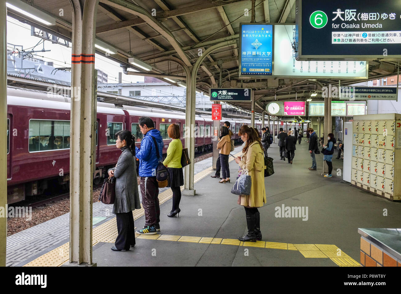 Pendolari su una piattaforma presso la Stazione di Juso lungo la ferrovia Hankyu Kobe linea. Questo è uno dei tre principali commuter rail in linee di Kobe area di Osaka. Foto Stock