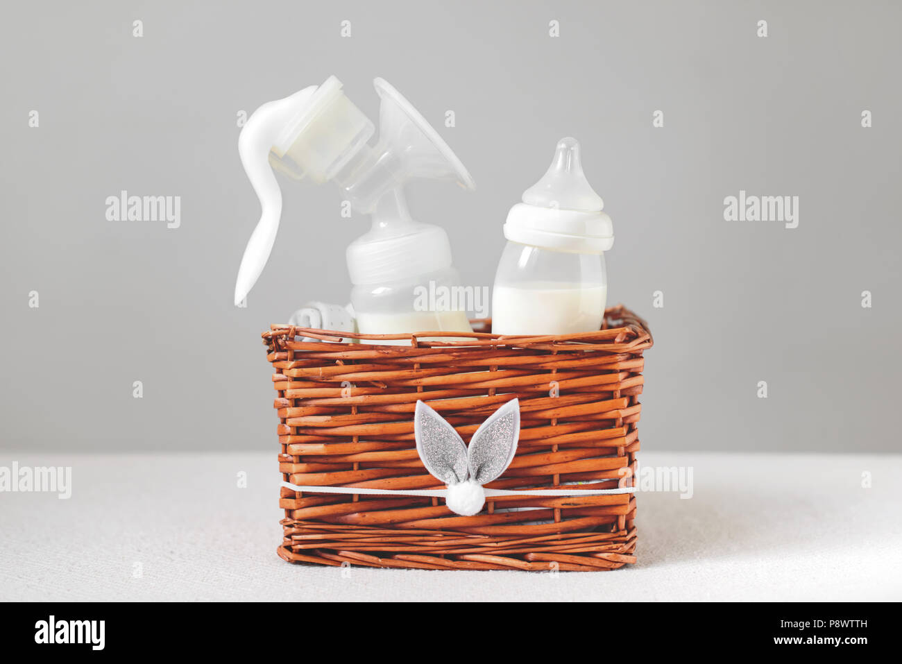 Tiralatte e bottiglia con latte per il bambino in una cesta di paglia. Copia gratuita dello spazio. Foto Stock