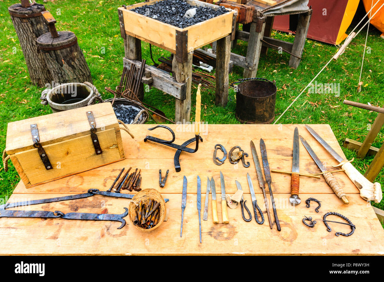 Rievocazione, storia vivente. Display sulla tabella dei vari strumenti che sono realizzati da fabbro medievale, coltelli, strumenti e pugnali. Foto Stock